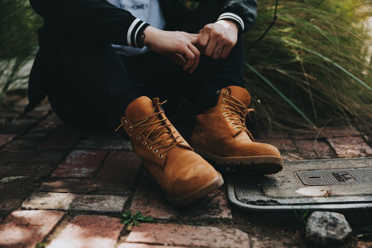 A person sitting on bricks wearing untied boots.