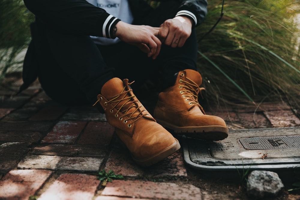 person sitting on gray pavement beside grass