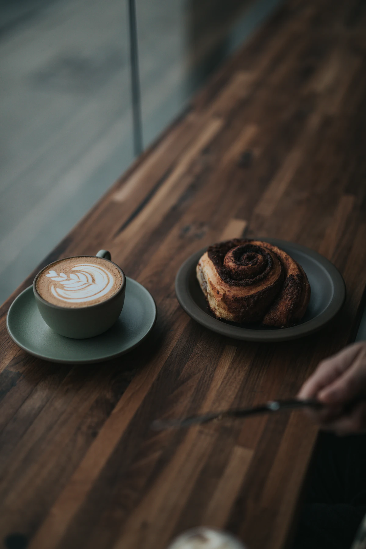A flat white with leaf latte art on a sunny café table