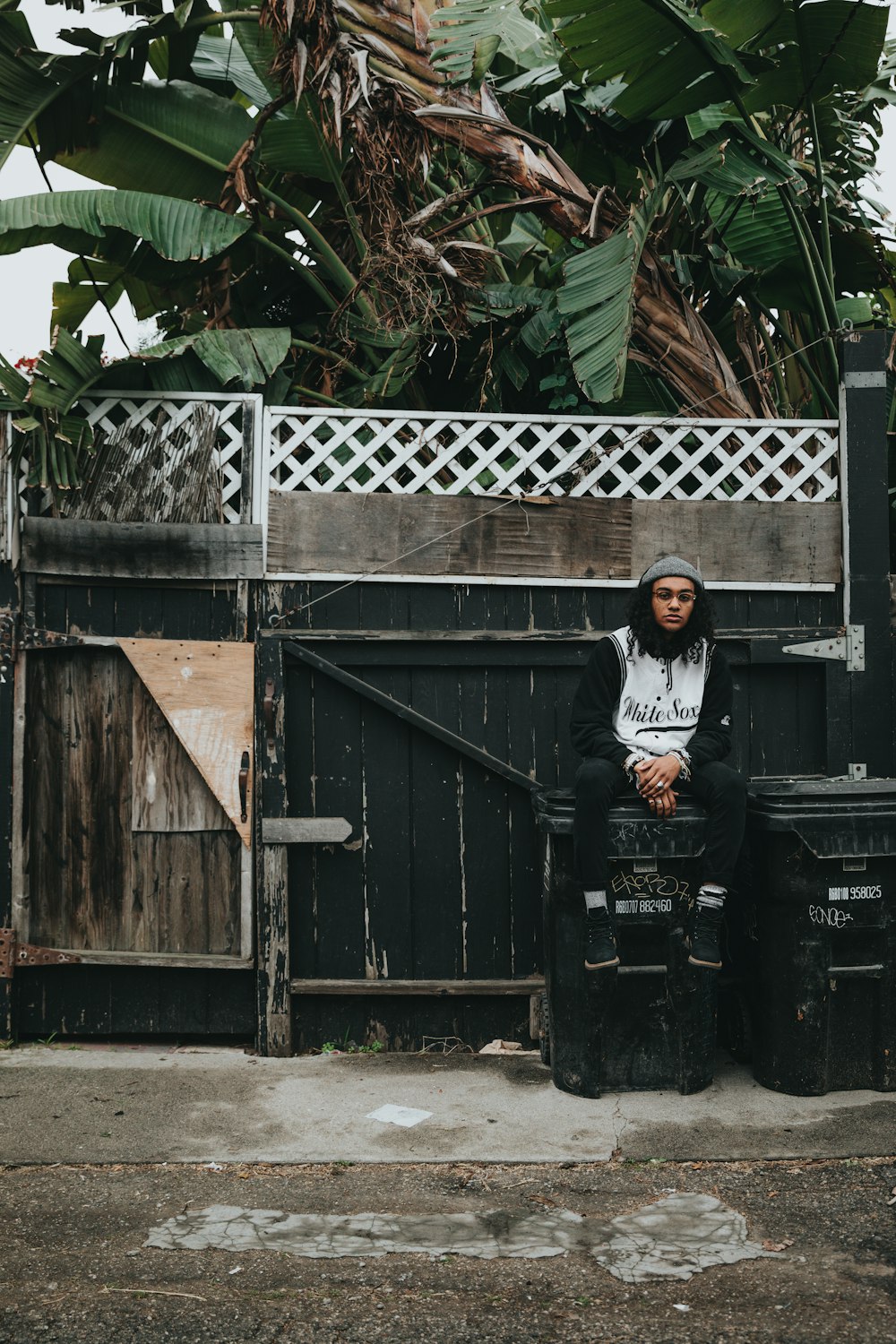 man sitting on black plastic trash bin