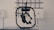 A black, mechanical device with a central structure enclosed in a circular frame is set against a gray industrial background. The device appears complex with multiple joints and components, possibly for engineering or robotics applications.
