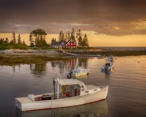 red house beside body of water with white motor boats during daytime