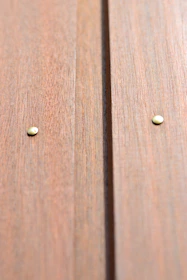 Close-up of rustic industrial nails piled on a wooden surface with yellow lighting.