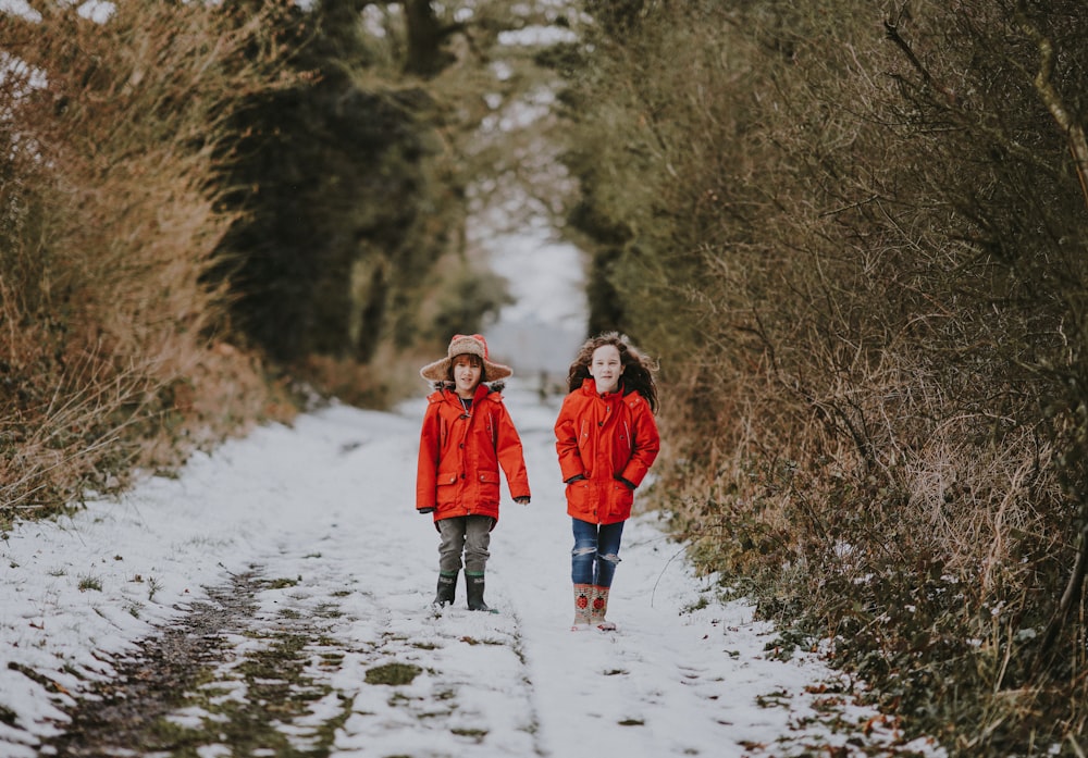 Zwei Kinder gehen im Winter in der Nähe von Büschen spazieren