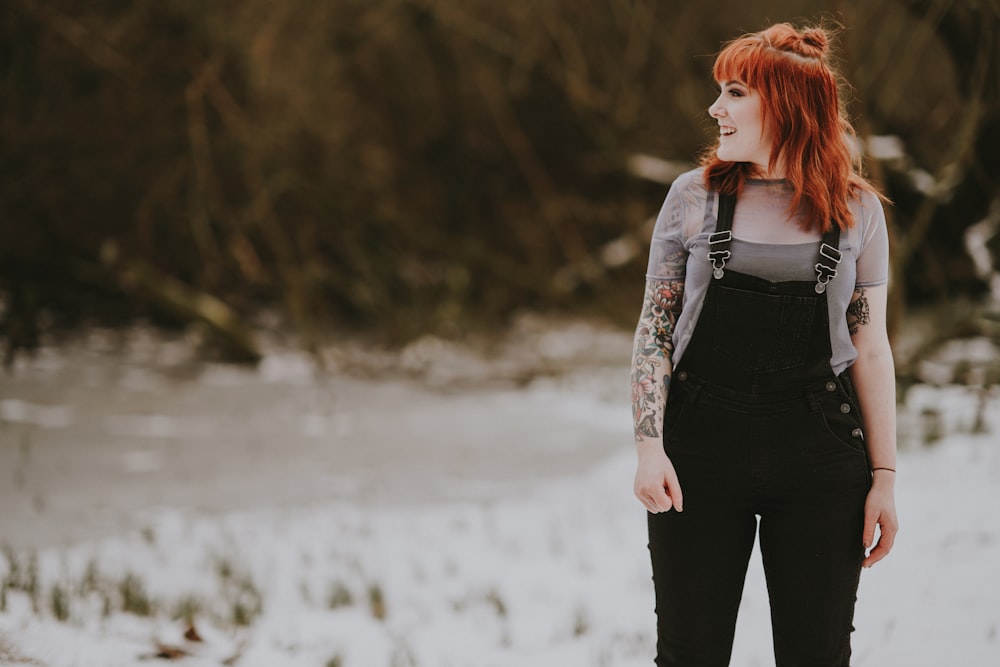 smiling woman wearing black overalls standing on white ground at daytime