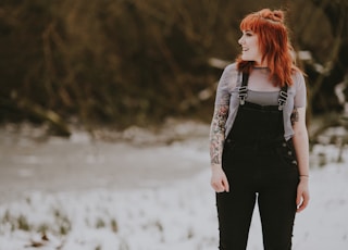 smiling woman wearing black overalls standing on white ground at daytime
