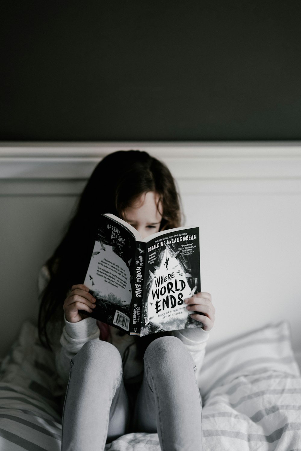 girl reading book on bed
