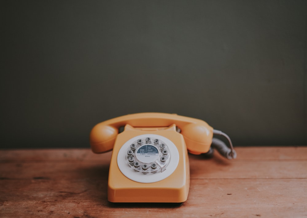 Téléphone à cadran marron dans une chambre peinte en gris
