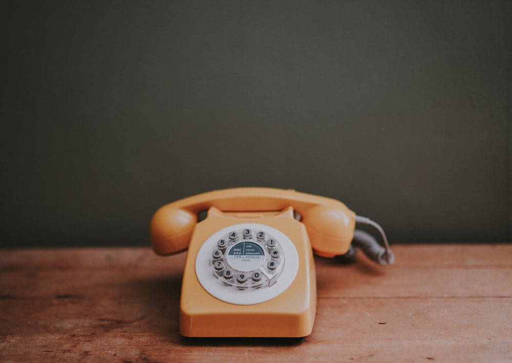 Telefone com discagem rotativa marrom no quarto pintado de cinza