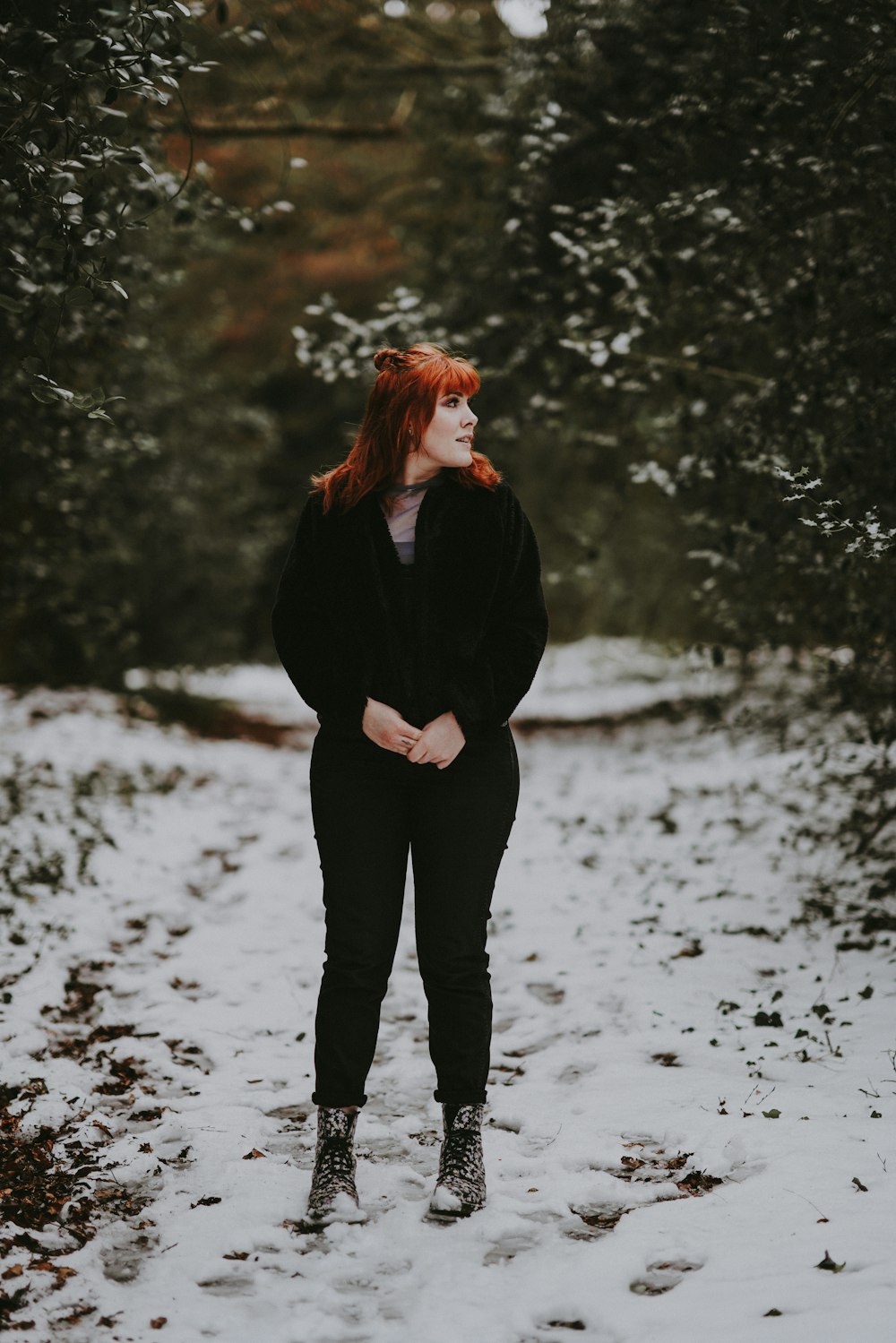 woman standing between green leaf plants