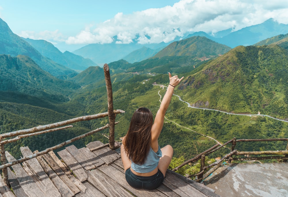 woman raising hand on mountain top