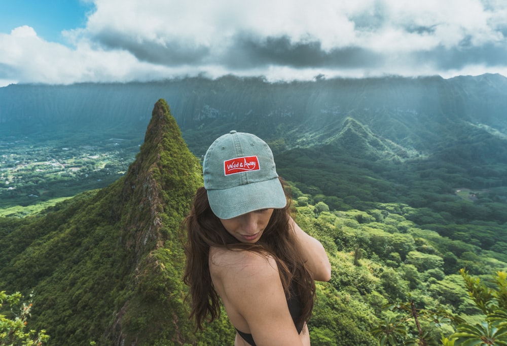 woman wearing gray cap standing near mountain
