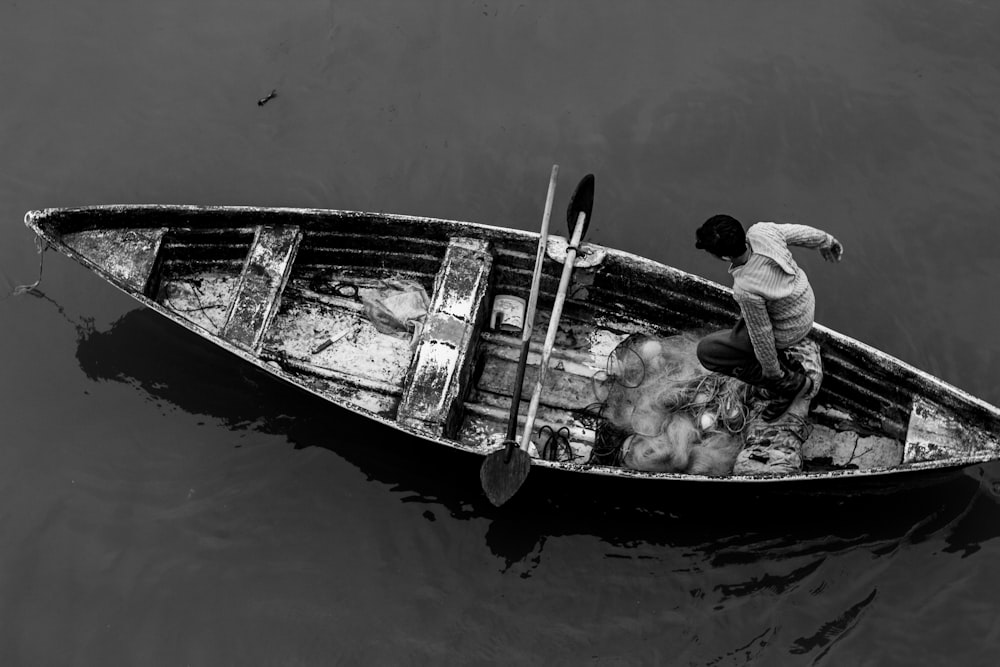 grayscale photography of man standing on boat