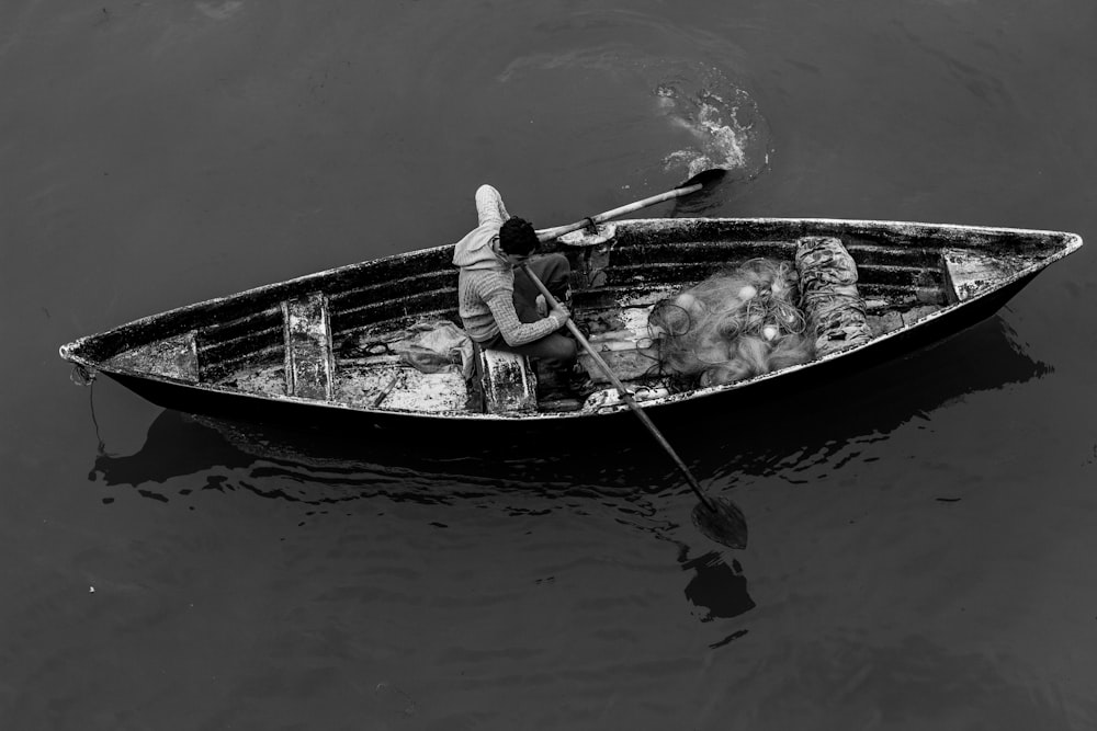 Foto in scala di grigi di un uomo in canoa