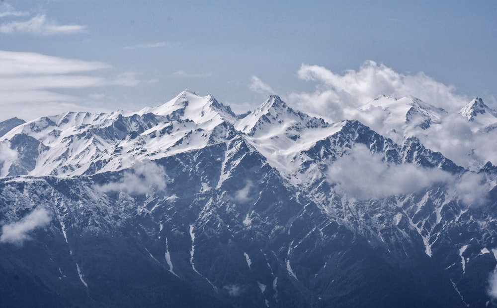 snow-covered mountains with white clouds during daytime