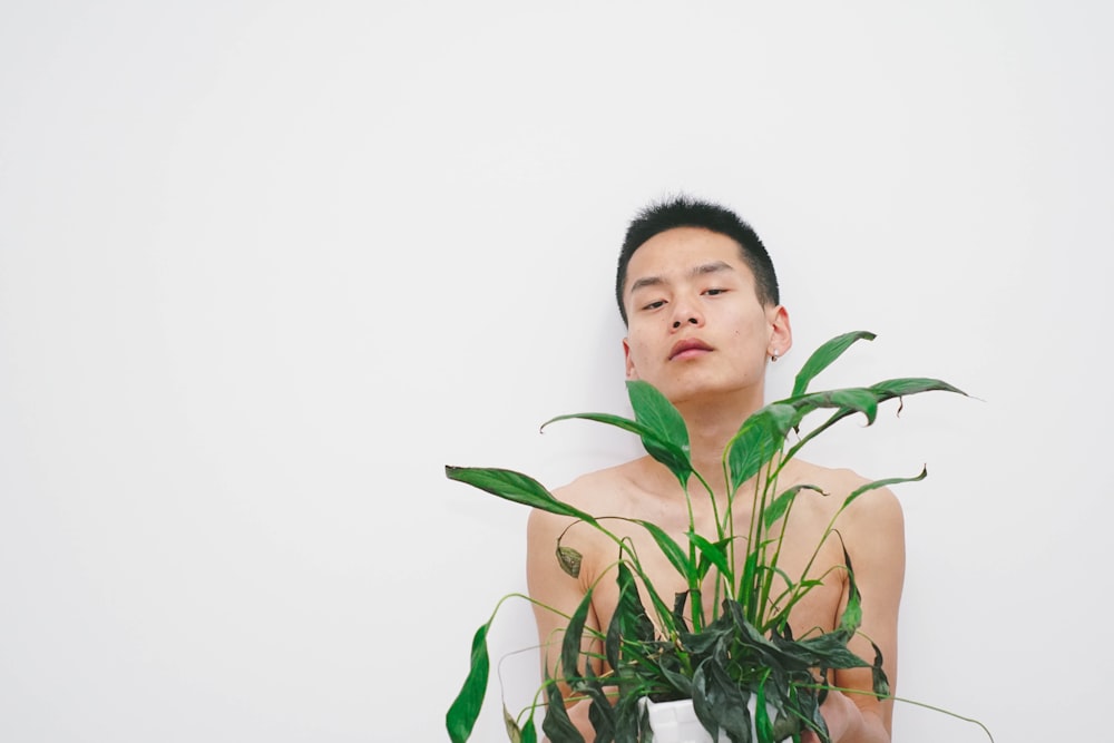 man holding green leaf plant with white background