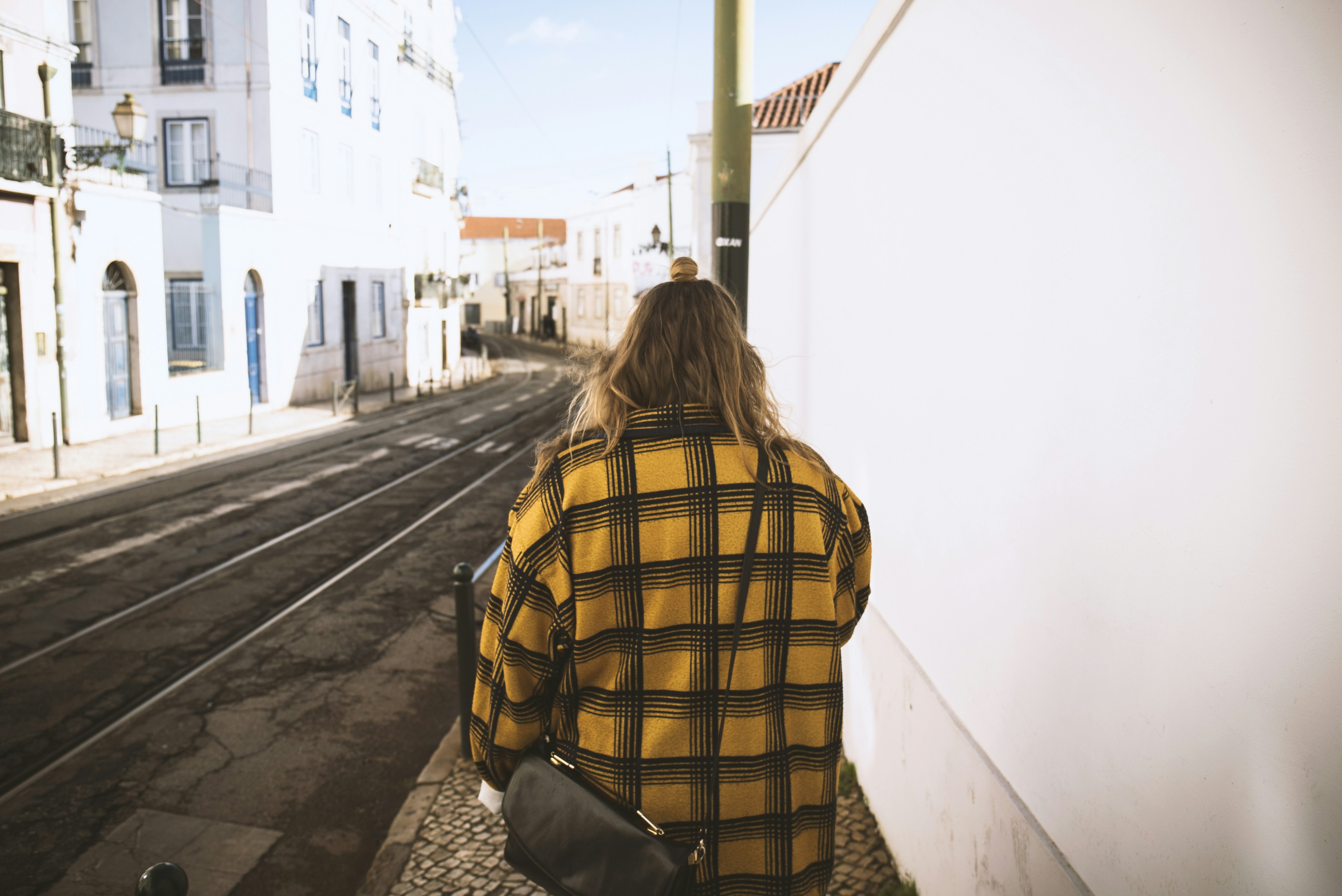 Femme marchant tranquillement le long d un mur blanc texturé illustrant la découverte à pied
