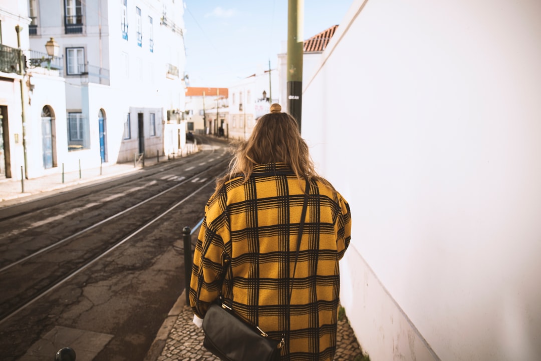 woman walking beside white concrete wall