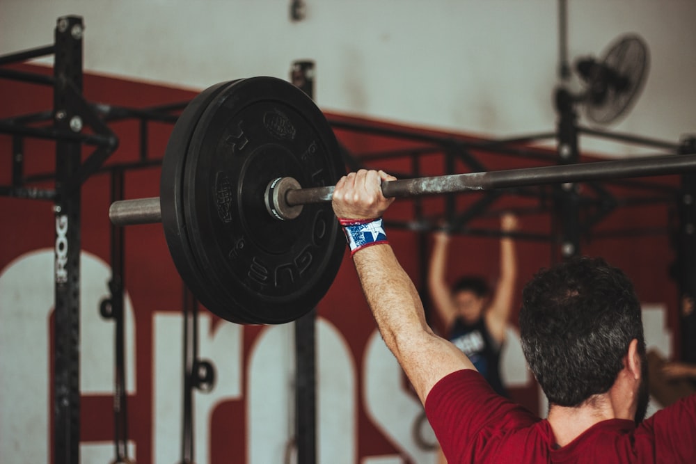 uomo che porta bilanciere in palestra