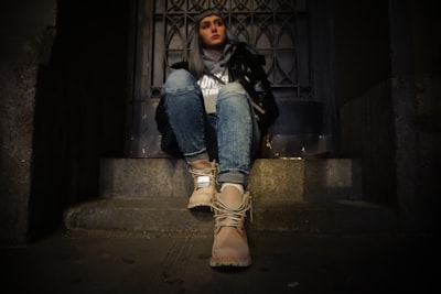 woman sitting on top of gray concrete stair near door leg google meet background