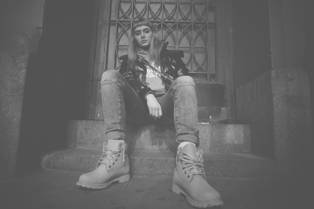 grayscale photo of woman sitting on concrete stair