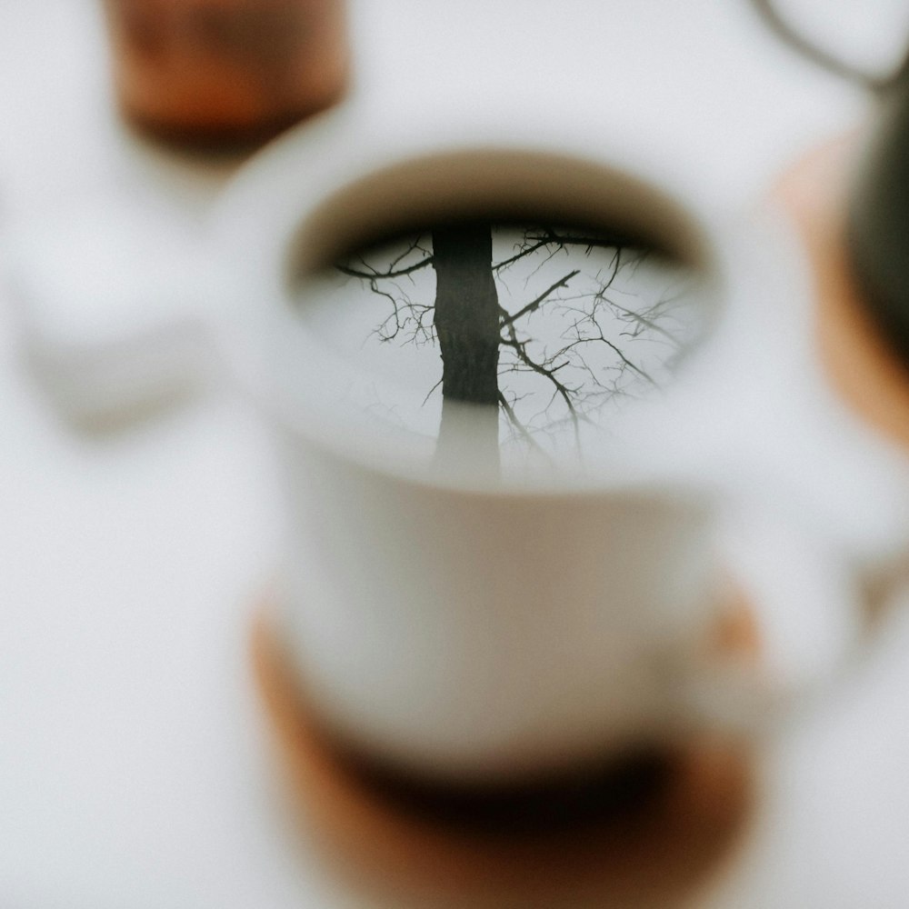 a coffee cup with a reflection of a tree in it