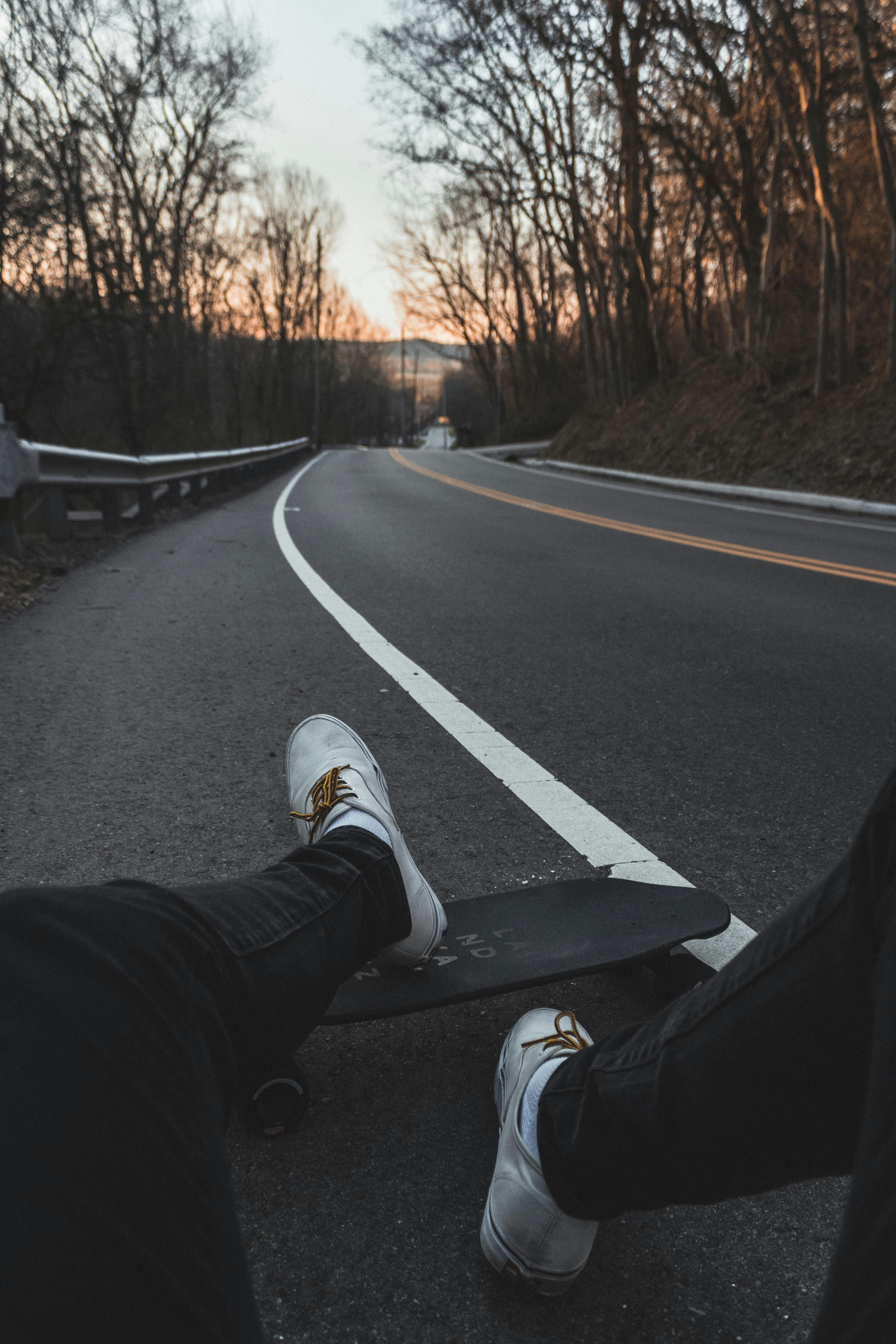 person sitting on road with longboard