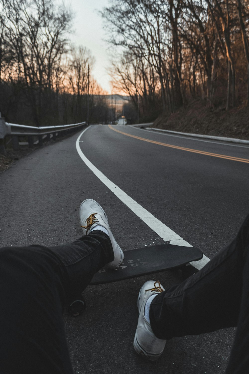 person sitting on road with longboard