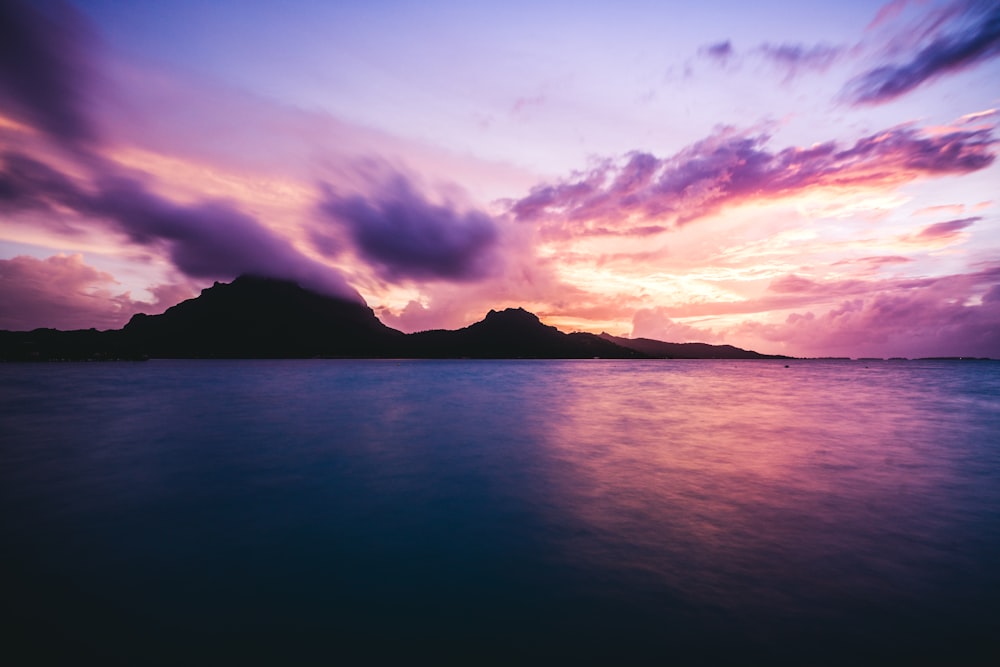 low-angle photography of mountain near body of water