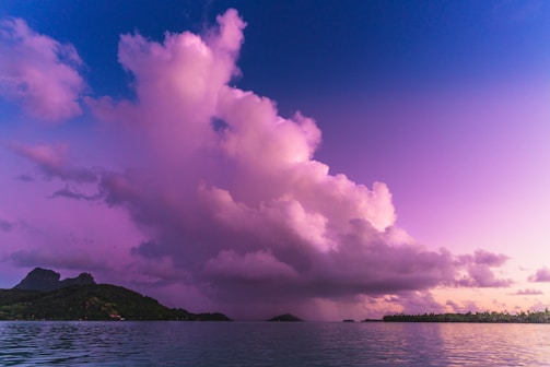 A vibrant sunset over a tropical island beach with colorful hostel lights glowing.