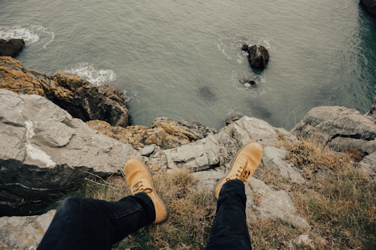 person wearing brown work boots sitting on cliff in Dublin Ireland