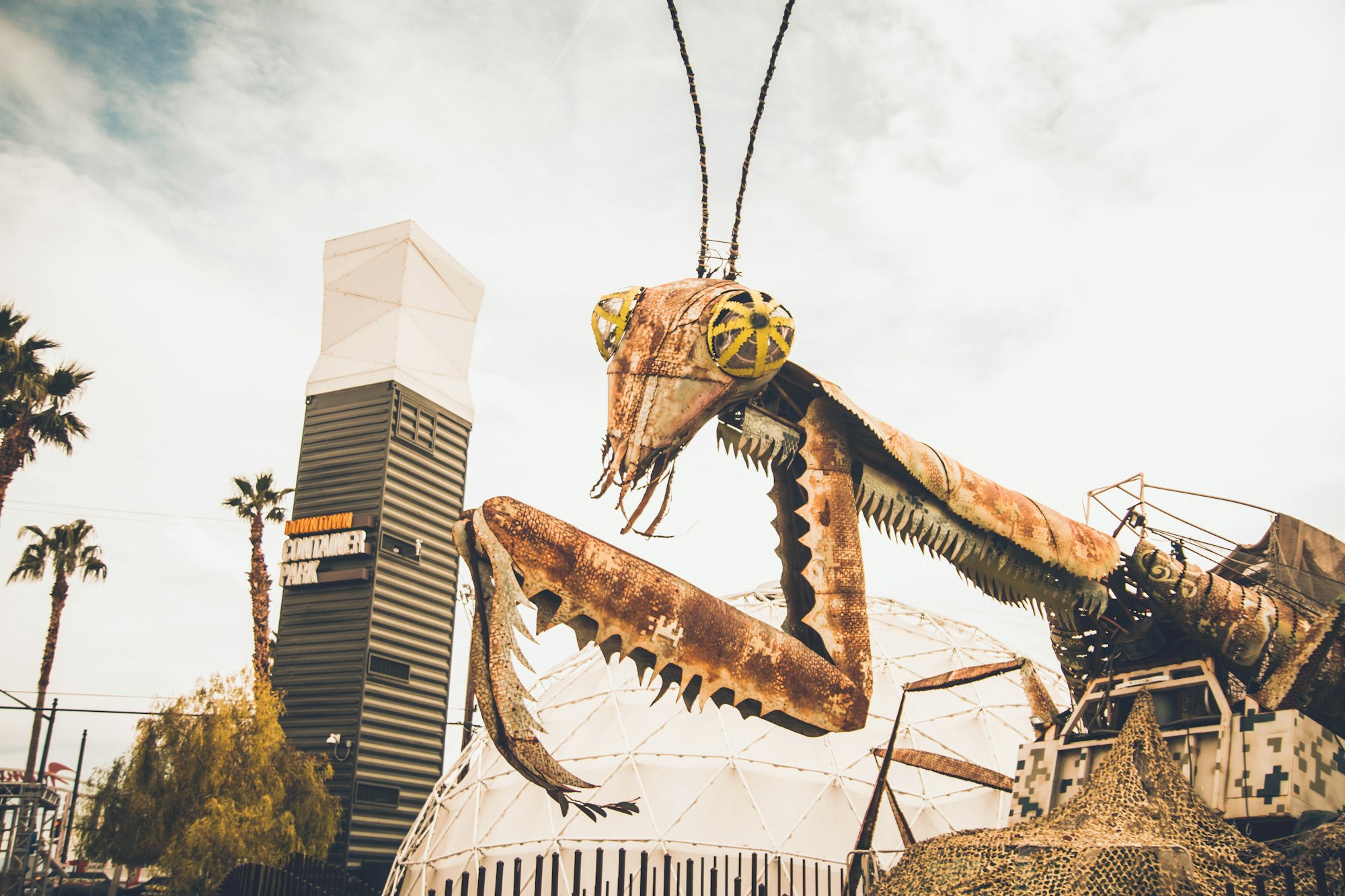 A large art installation of a preying mantic, made from oxidized metal.