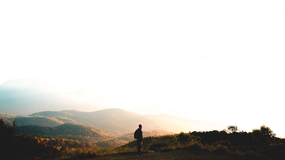 man standing near mountain under cloudy sky at daytime