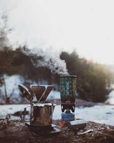 A compact camping stove glowing warmly amid a forest setting, emphasizing its sturdy design and reliable performance.