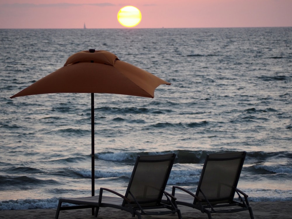 바닷가 근처에 빨간 우산이 있는 2개의 안락 의자