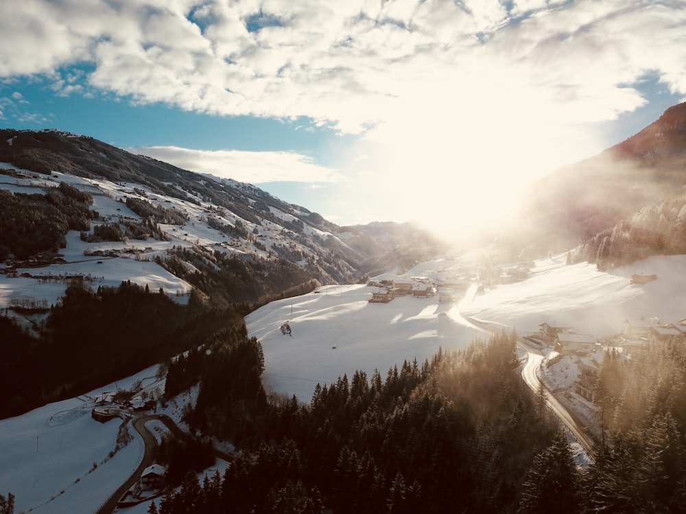 aerial view of forest surrounded with snow under blue and white cloudy sky