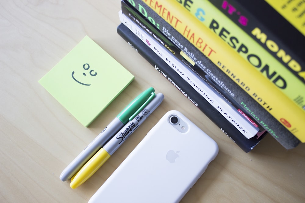 dois marcadores Sharpie ao lado do iPhone e notas adesivas