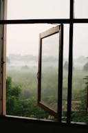 an open window with a view of a foggy field