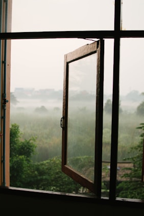 A serene early morning scene viewed through a softly fogged window, hinting at quiet reflection.