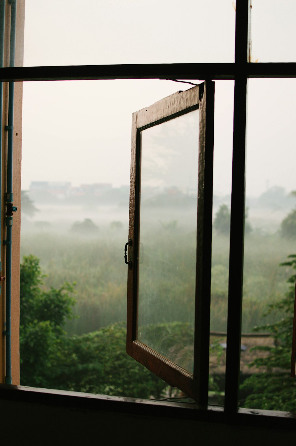 ein offenes Fenster mit Blick auf ein nebliges Feld