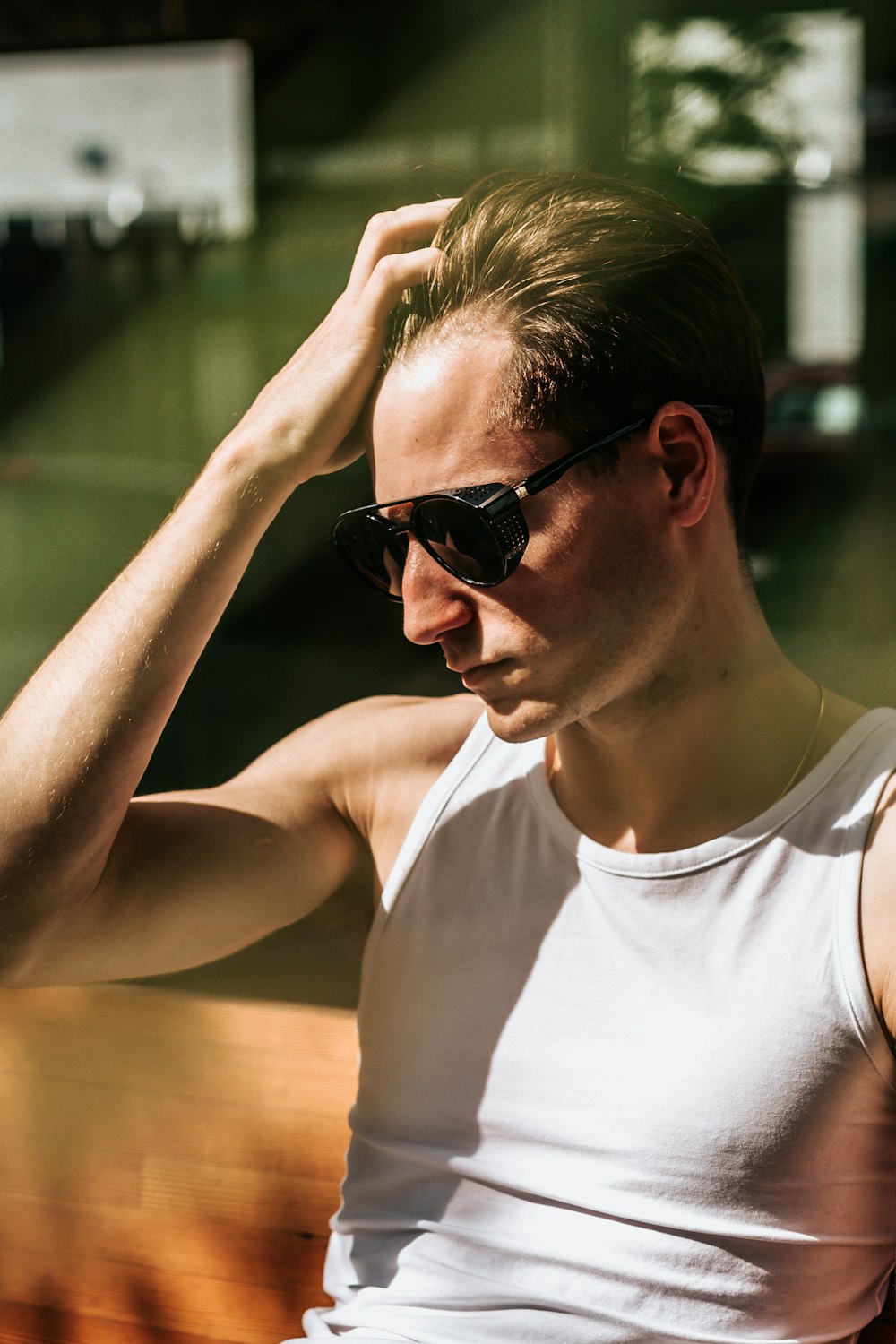 man sitting while holding his hair taken at daytime