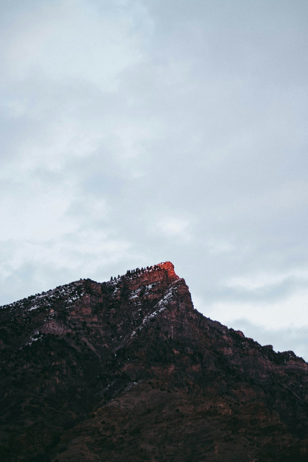 brown rocky mountain under gray sky