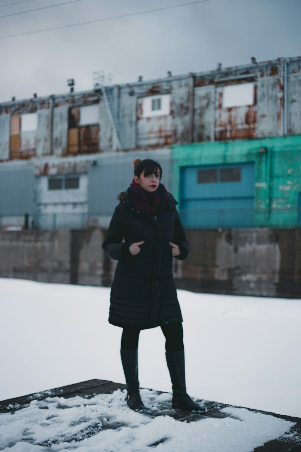 selective focus photography of woman wearing overcoat standing on intermodal container