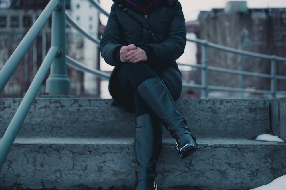 mulher sentada na escada de concreto cinza