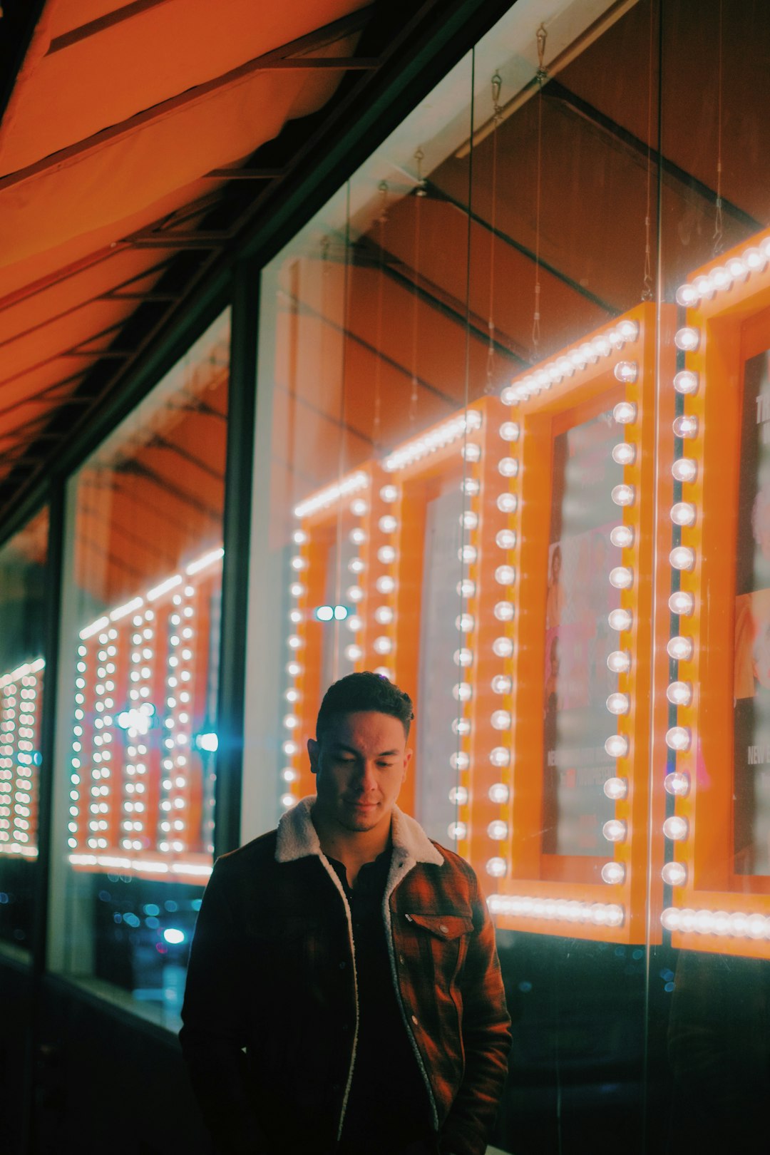 man wearing brown zip-up jacket standing beside clear glass wall