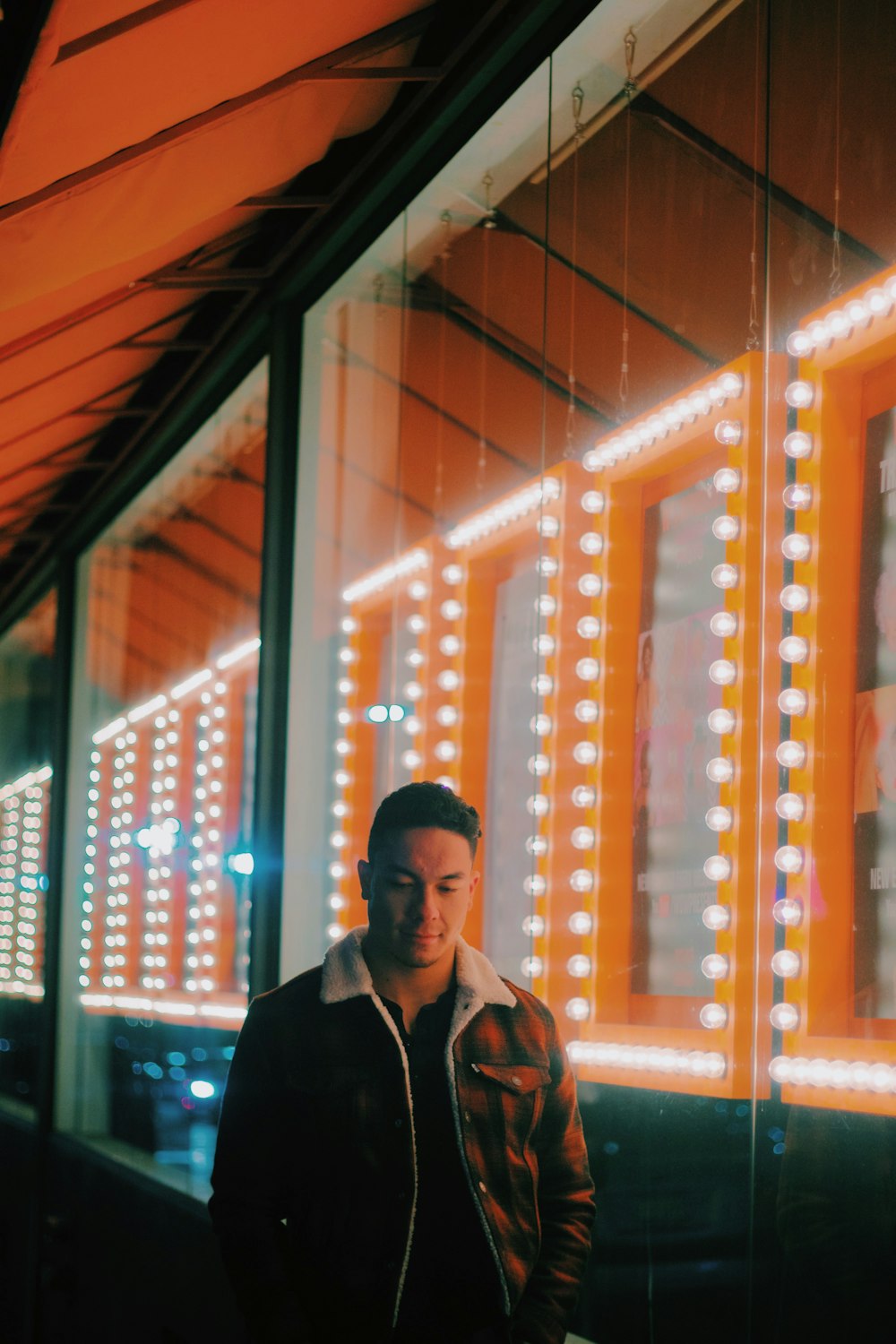 man wearing brown zip-up jacket standing beside clear glass wall