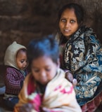 focus photography of woman sitting besides two toddlers