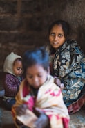 focus photography of woman sitting besides two toddlers
