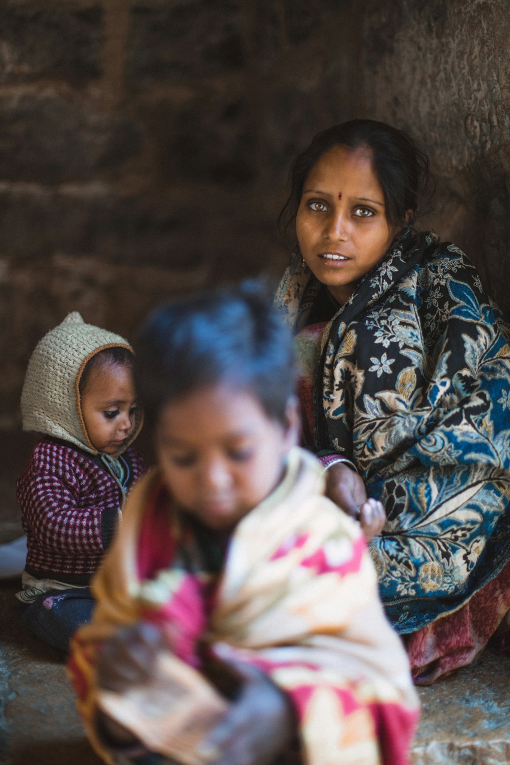 focus photography of woman sitting besides two toddlers