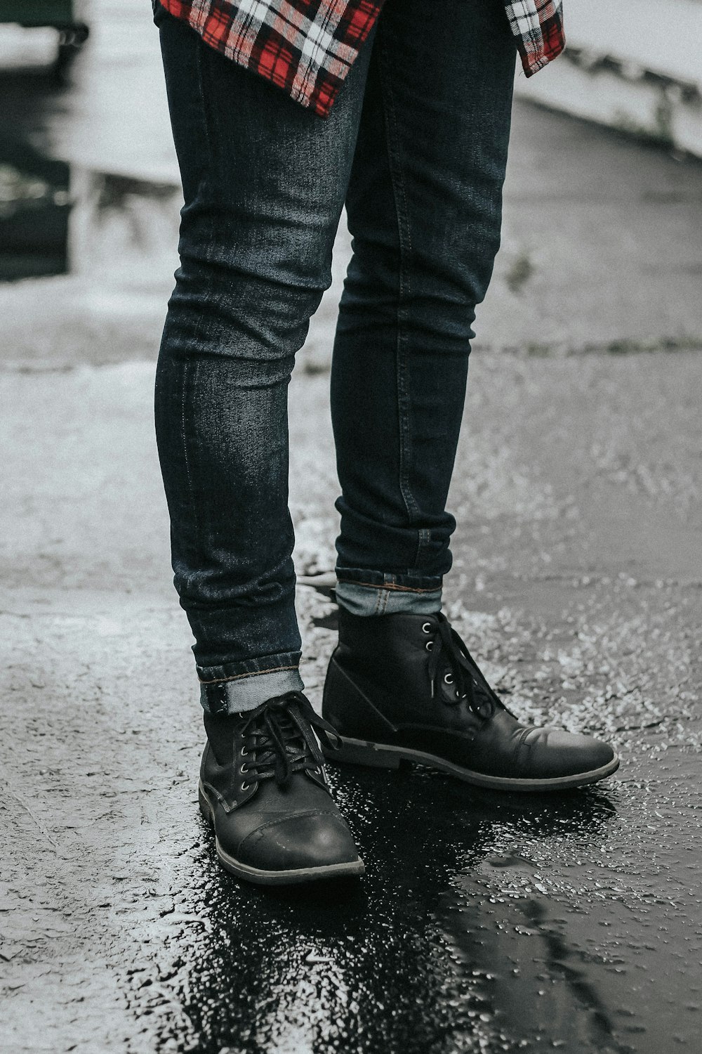 person wearing black denim jeans and pair of black leather boots